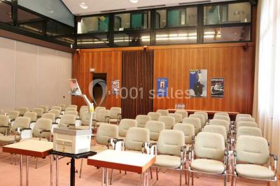 Salle de réunion lumineuse avec table ovale, chaises, paperboard et vue sur la Tour Eiffel à travers de grandes fenêtres.