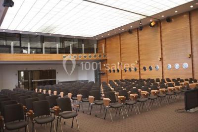 Salle de réunion lumineuse avec table ovale, chaises, paperboard et vue sur la Tour Eiffel à travers de grandes fenêtres.