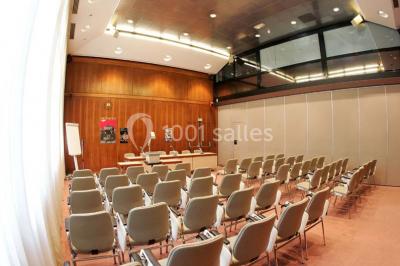 Salle de réunion lumineuse avec table ovale, chaises, paperboard et vue sur la Tour Eiffel à travers de grandes fenêtres.