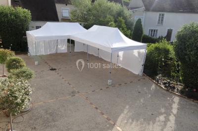 Salle spacieuse avec charpente en bois apparente, carrelage clair et plantes en pots alignées près des fenêtres.
