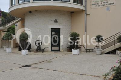 Salle spacieuse avec charpente en bois apparente, carrelage clair et plantes en pots alignées près des fenêtres.