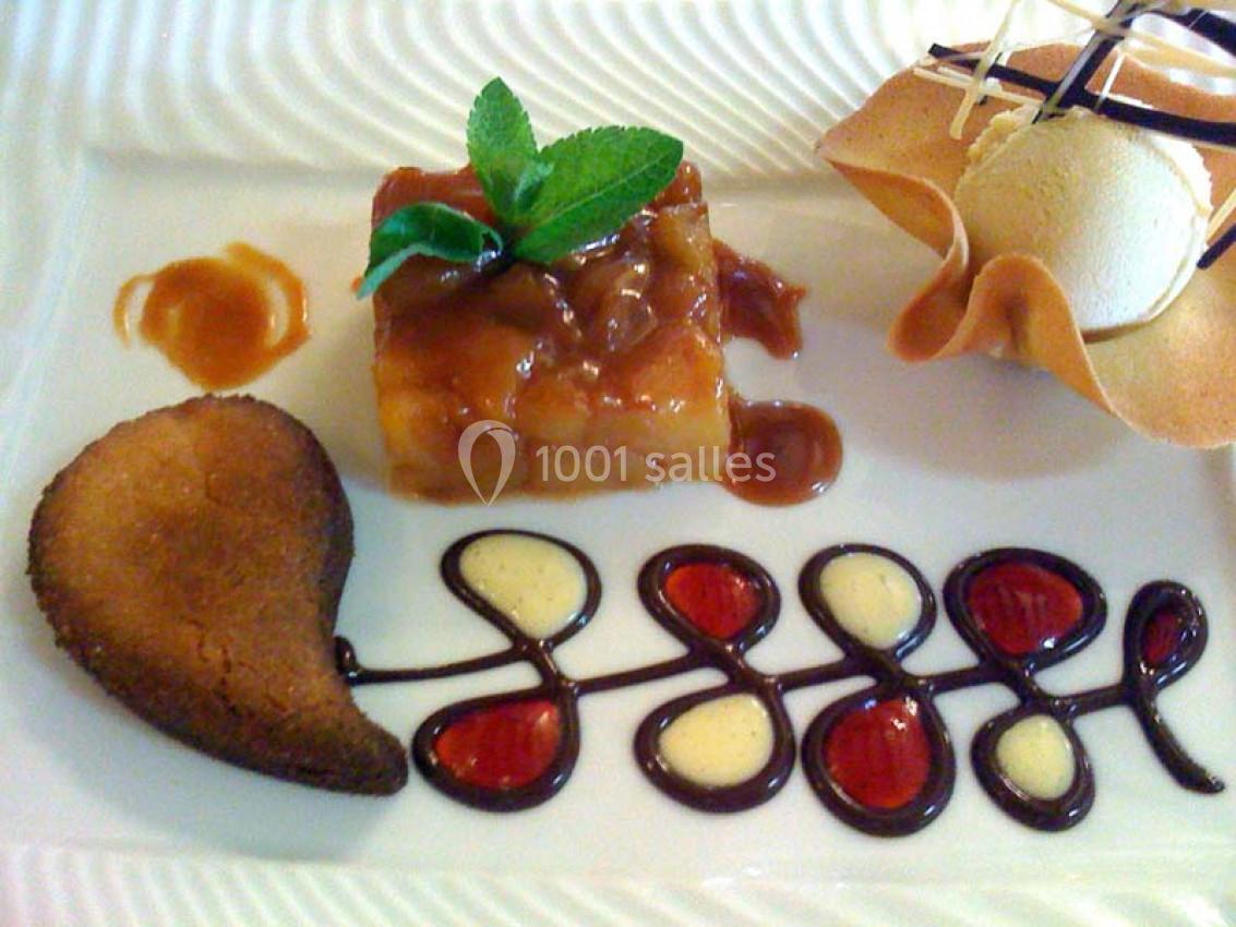 Dessert composé d'un gâteau caramélisé, d'une glace dans une tuile croustillante et d'une décoration en sauce chocolat.