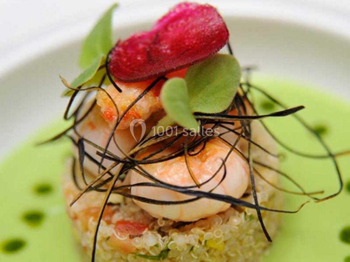 Plat gastronomique composé de crevettes, quinoa, légumes verts, algues et une sauce verte en fond.