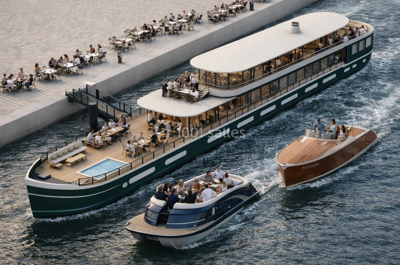 Bateau de croisière moderne naviguant sur un canal, accompagné de deux bateaux plus petits, près d'une terrasse animée.