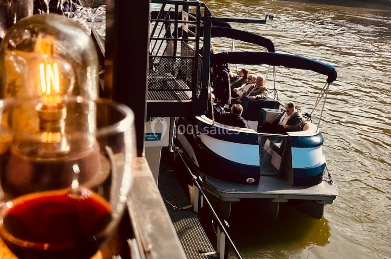 Un groupe de personnes assises sur un petit bateau amarré près d'un quai, avec un verre de vin au premier plan.