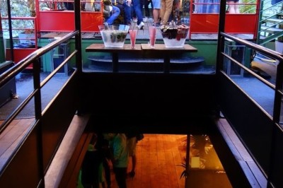 Vue d'un escalier menant à une terrasse animée avec des personnes discutant autour de tables et de plantes.