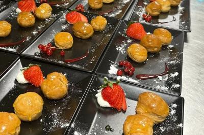 Salle de réception décorée avec des tables rondes et rectangulaires, nappes blanches, chaises blanches et guirlandes…