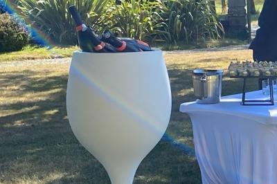 Salle de réception décorée avec des tables rondes et rectangulaires, nappes blanches, chaises blanches et guirlandes…