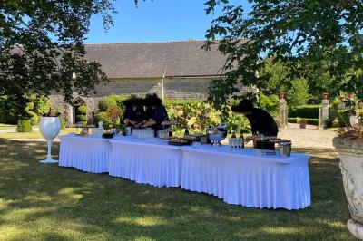 Salle de réception décorée avec des tables rondes et rectangulaires, nappes blanches, chaises blanches et guirlandes…