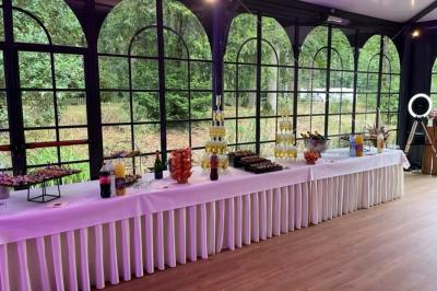 Salle de réception décorée avec des tables rondes et rectangulaires, nappes blanches, chaises blanches et guirlandes…