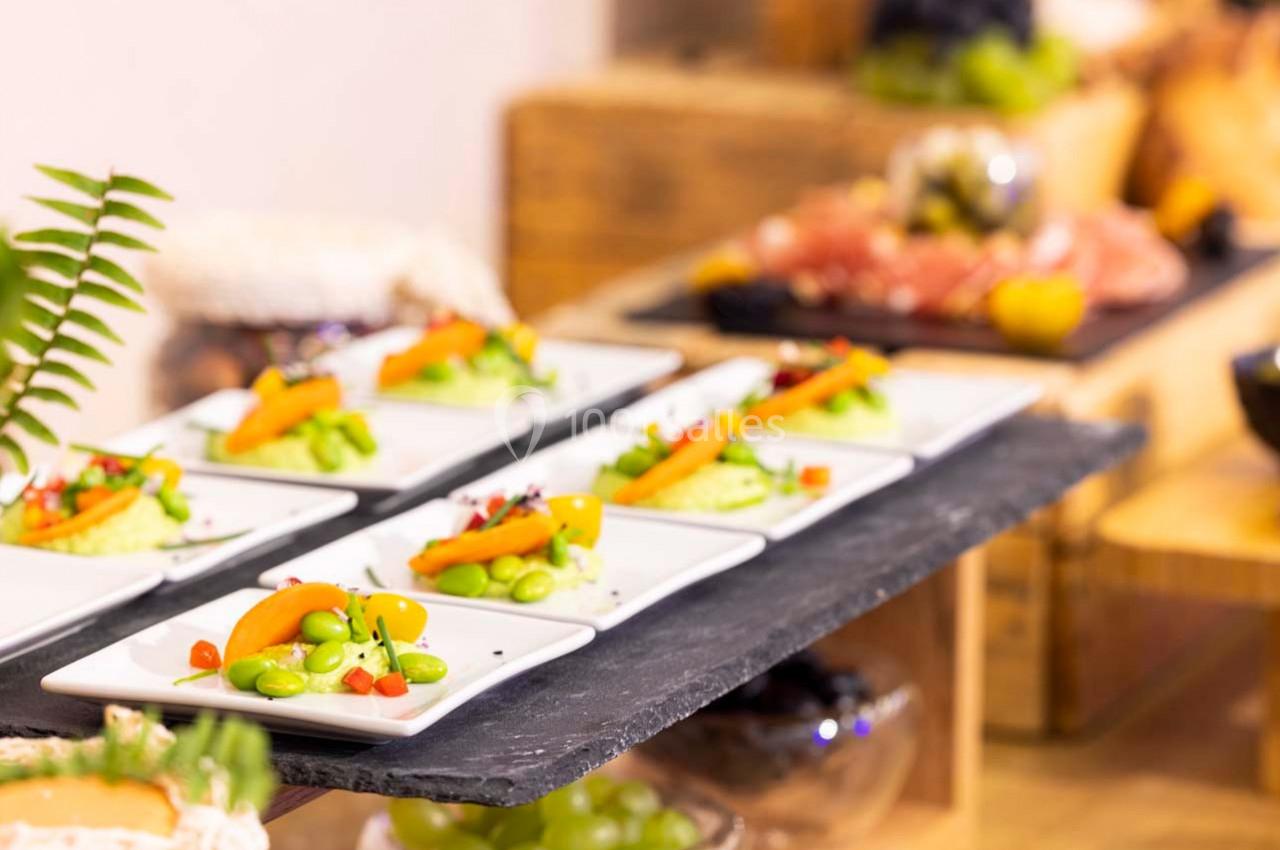 Assiettes individuelles garnies de légumes frais et colorés, disposées sur une table en ardoise dans un buffet.