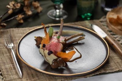 Dessert au chocolat garni de mangue, copeaux de noix de coco et pistaches, présenté sur une assiette verte.
