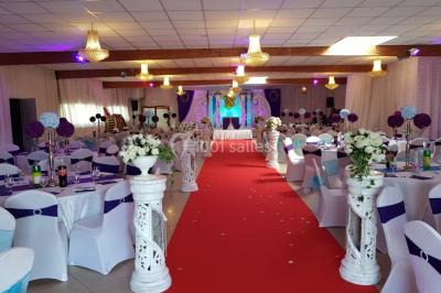 Des personnes discutent devant un bâtiment avec des voitures garées, dont une sportive rouge au premier plan.