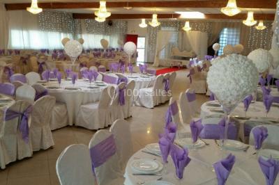 Des personnes discutent devant un bâtiment avec des voitures garées, dont une sportive rouge au premier plan.