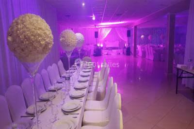 Des personnes discutent devant un bâtiment avec des voitures garées, dont une sportive rouge au premier plan.