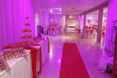 Des personnes discutent devant un bâtiment avec des voitures garées, dont une sportive rouge au premier plan.