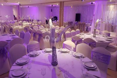 Des personnes discutent devant un bâtiment avec des voitures garées, dont une sportive rouge au premier plan.