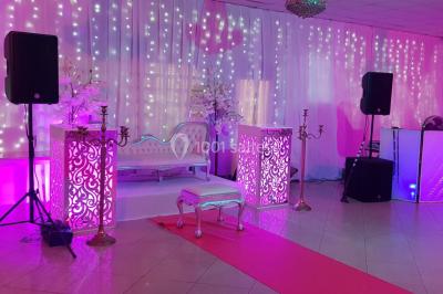 Des personnes discutent devant un bâtiment avec des voitures garées, dont une sportive rouge au premier plan.