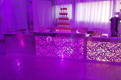 Des personnes discutent devant un bâtiment avec des voitures garées, dont une sportive rouge au premier plan.