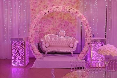 Des personnes discutent devant un bâtiment avec des voitures garées, dont une sportive rouge au premier plan.