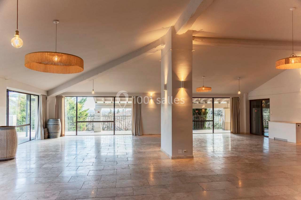 Salle spacieuse et lumineuse avec de grandes baies vitrées, un sol en pierre et des suspensions en osier.