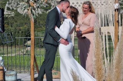 Un couple en tenue de mariage pose dans un champ d'oliviers sous une lumière douce.