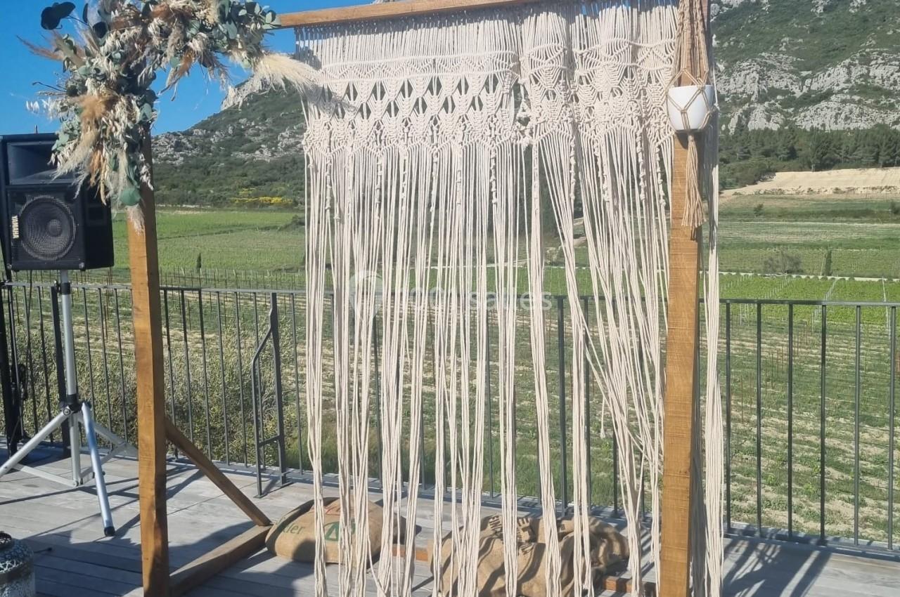 Arche en bois décorée de macramé et de fleurs séchées, installée en extérieur avec vue sur des montagnes.