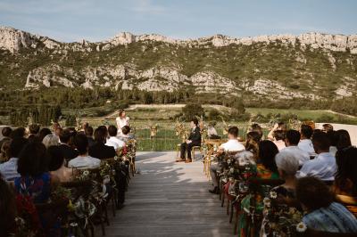 Un couple en tenue de mariage pose dans un champ d'oliviers sous une lumière douce.