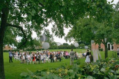 Banc en bois sous une arche décorée de feuilles d'automne, entouré de bougies et de feuilles au sol dans une salle rustique.