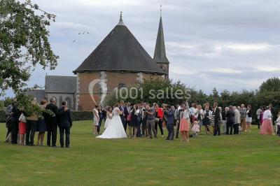 Banc en bois sous une arche décorée de feuilles d'automne, entouré de bougies et de feuilles au sol dans une salle rustique.