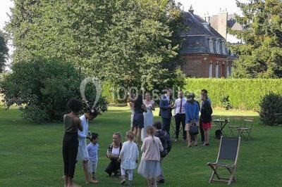 Banc en bois sous une arche décorée de feuilles d'automne, entouré de bougies et de feuilles au sol dans une salle rustique.