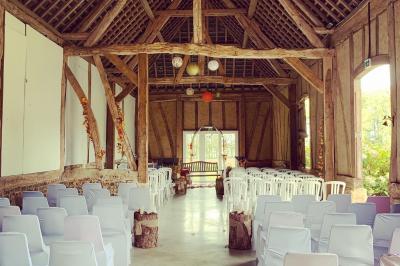 Banc en bois sous une arche décorée de feuilles d'automne, entouré de bougies et de feuilles au sol dans une salle rustique.