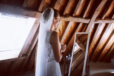 Banc en bois sous une arche décorée de feuilles d'automne, entouré de bougies et de feuilles au sol dans une salle rustique.