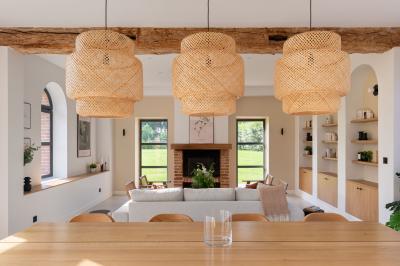 Banc en bois sous une arche décorée de feuilles d'automne, entouré de bougies et de feuilles au sol dans une salle rustique.