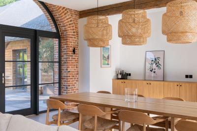 Banc en bois sous une arche décorée de feuilles d'automne, entouré de bougies et de feuilles au sol dans une salle rustique.