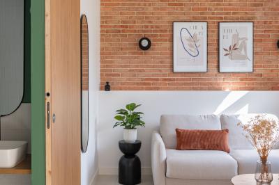 Banc en bois sous une arche décorée de feuilles d'automne, entouré de bougies et de feuilles au sol dans une salle rustique.