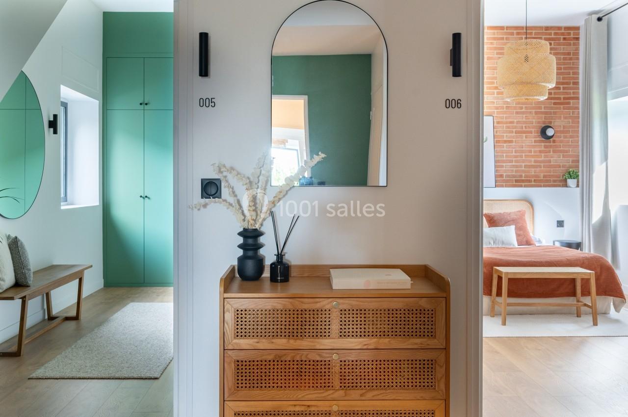 Meuble en bois avec miroir au mur, encadré par deux portes numérotées, dans un intérieur lumineux et moderne.