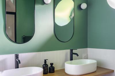 Banc en bois sous une arche décorée de feuilles d'automne, entouré de bougies et de feuilles au sol dans une salle rustique.