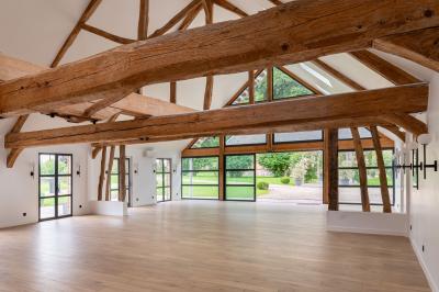 Banc en bois sous une arche décorée de feuilles d'automne, entouré de bougies et de feuilles au sol dans une salle rustique.