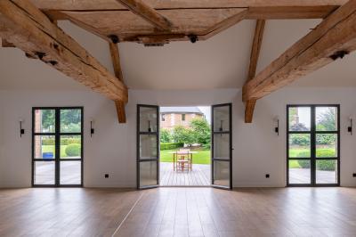 Banc en bois sous une arche décorée de feuilles d'automne, entouré de bougies et de feuilles au sol dans une salle rustique.