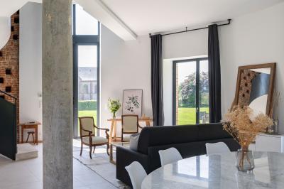 Banc en bois sous une arche décorée de feuilles d'automne, entouré de bougies et de feuilles au sol dans une salle rustique.
