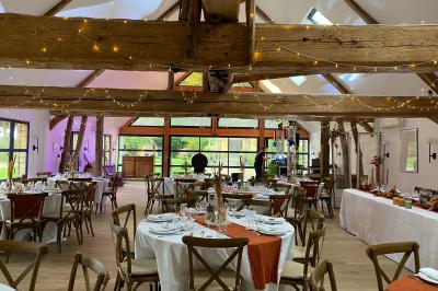 Banc en bois sous une arche décorée de feuilles d'automne, entouré de bougies et de feuilles au sol dans une salle rustique.
