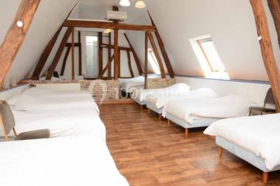 Lit double avec tête de lit sombre, draps gris et blancs, encadré par deux tables de chevet avec lampes, dans une chambre…