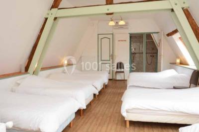 Lit double avec tête de lit sombre, draps gris et blancs, encadré par deux tables de chevet avec lampes, dans une chambre…