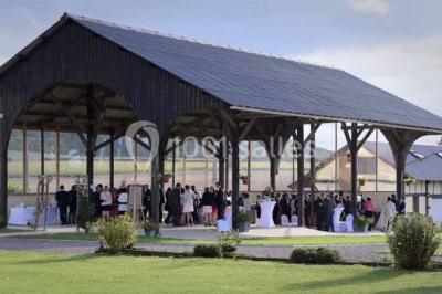 Lit double avec tête de lit sombre, draps gris et blancs, encadré par deux tables de chevet avec lampes, dans une chambre…
