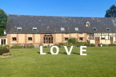 Lit double avec tête de lit sombre, draps gris et blancs, encadré par deux tables de chevet avec lampes, dans une chambre…