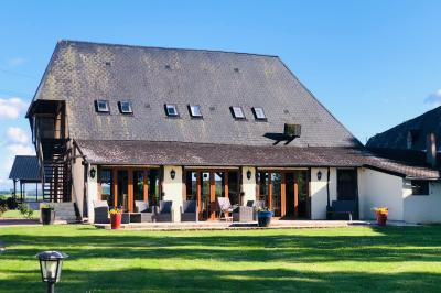 Lit double avec tête de lit sombre, draps gris et blancs, encadré par deux tables de chevet avec lampes, dans une chambre…