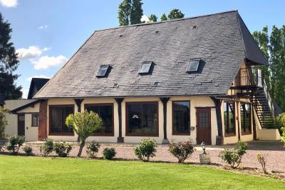 Lit double avec tête de lit sombre, draps gris et blancs, encadré par deux tables de chevet avec lampes, dans une chambre…
