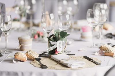Lit double avec tête de lit sombre, draps gris et blancs, encadré par deux tables de chevet avec lampes, dans une chambre…