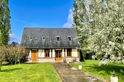 Lit double avec tête de lit sombre, draps gris et blancs, encadré par deux tables de chevet avec lampes, dans une chambre…